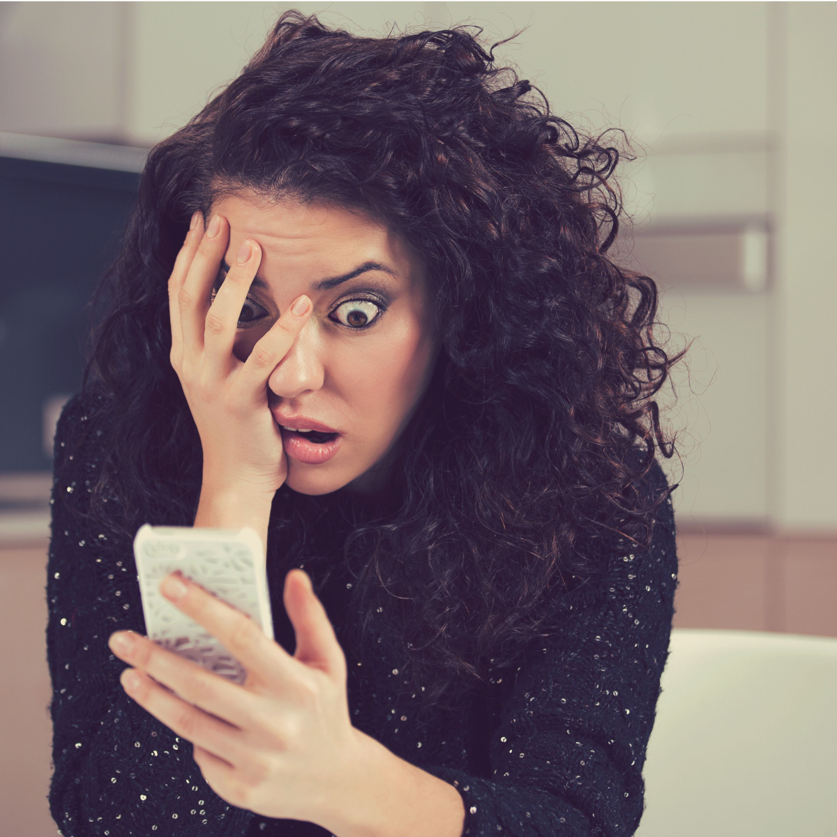 woman looking at cell phone in shocked manner