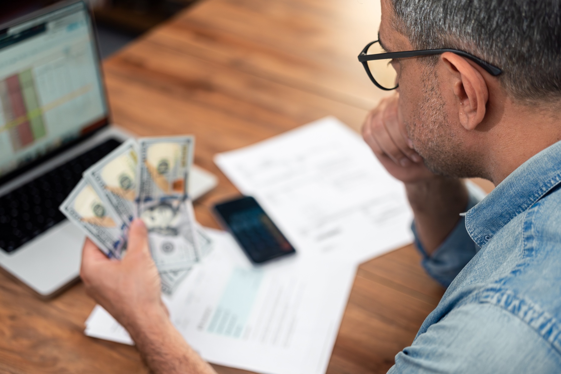 Worried person at a kitchen table reviewing household bills during the government shutdown.